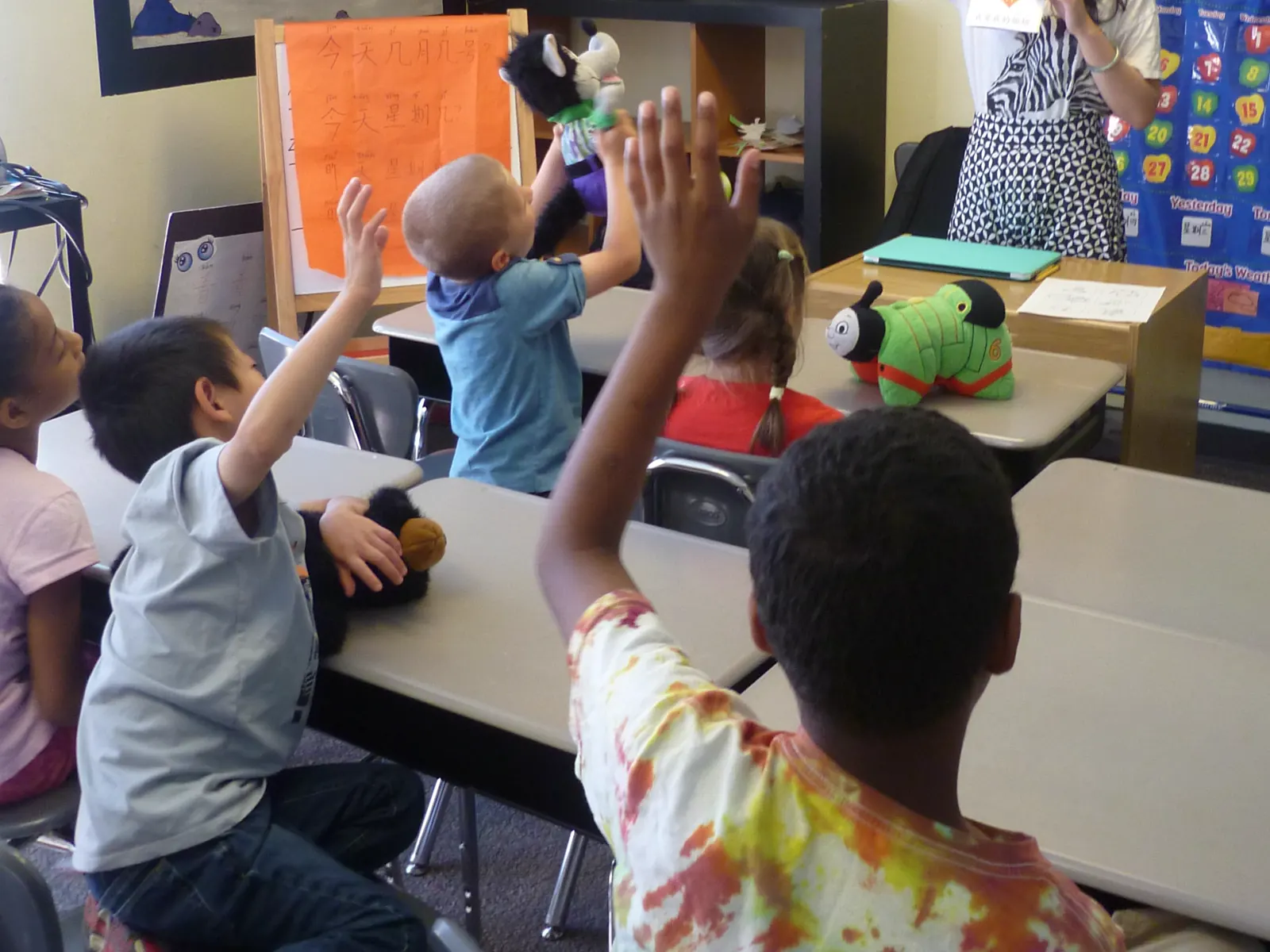 APLS students raising their hands in the classroom